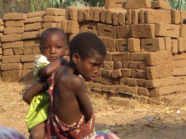 Orphan children with hand made bricks in the background.  Gogos have b...